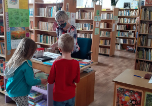 Nauczyciel bibliotekarz przyjmuje zwracane książki przez uczniów.